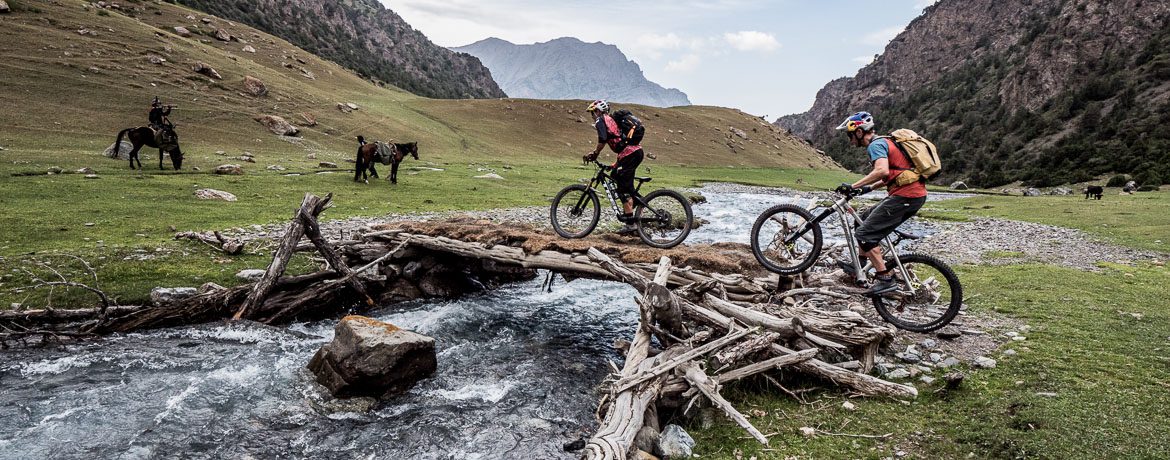 Rene Wildhaber and Tom Oehler crossing a bridge whilst mountain biking in Kyrgyzstan.